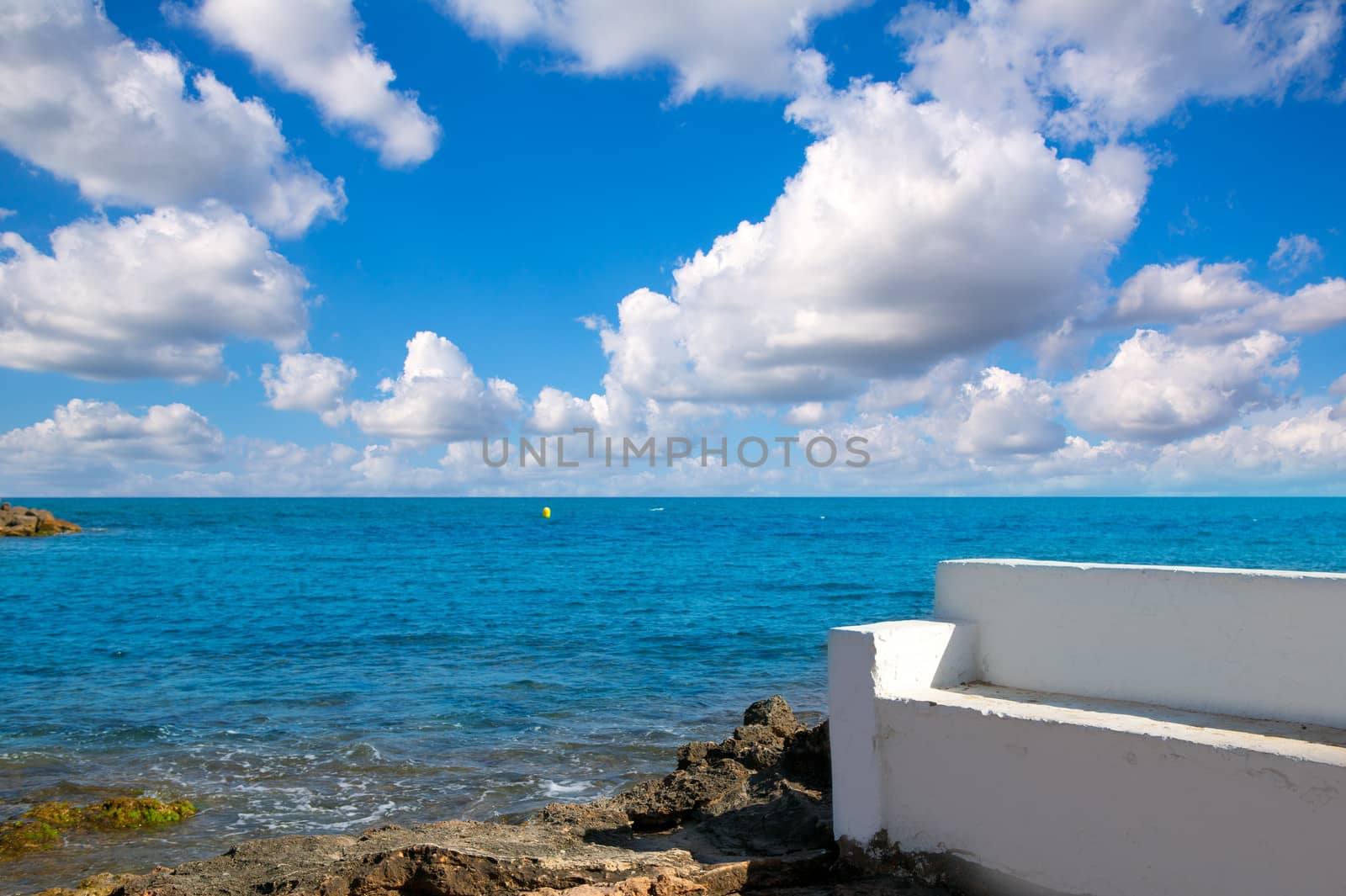 Torrevieja Alicante white bench in the shore rocks of Mediterranean sea