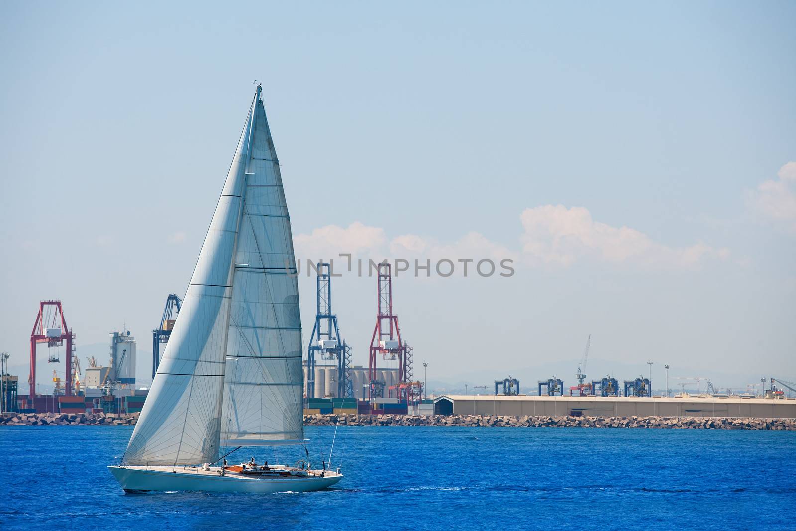 Valencia city port with sailboat and cranes in background by lunamarina