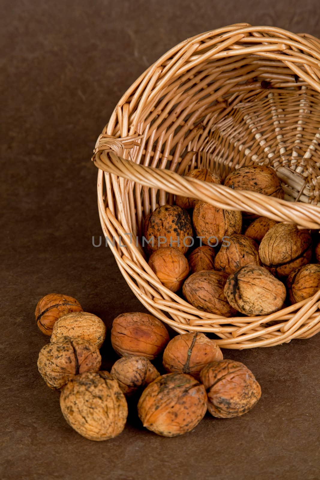 Walnuts in wicker basket on brown background