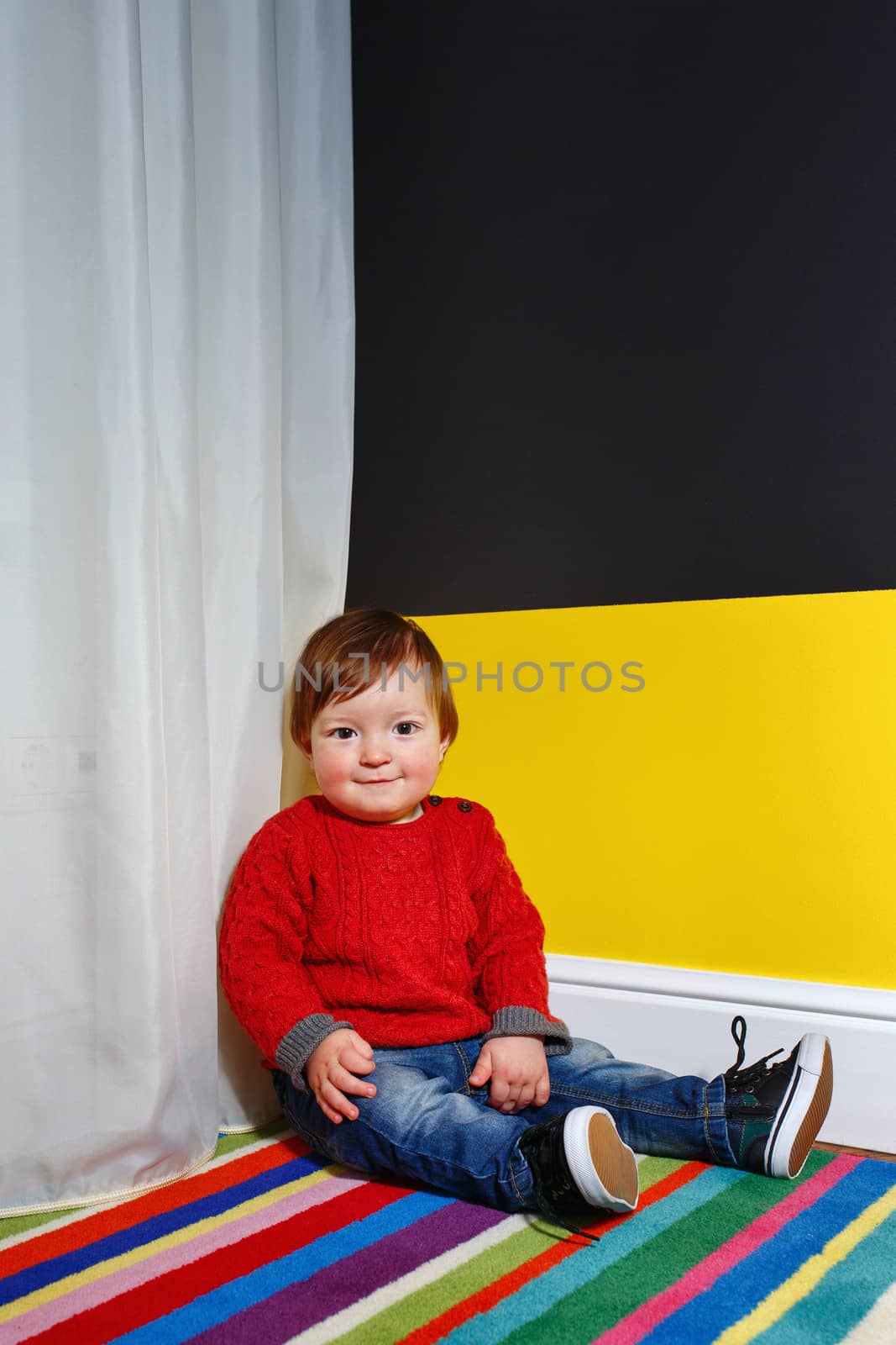 Cute little boy sitting on the floor in the living room