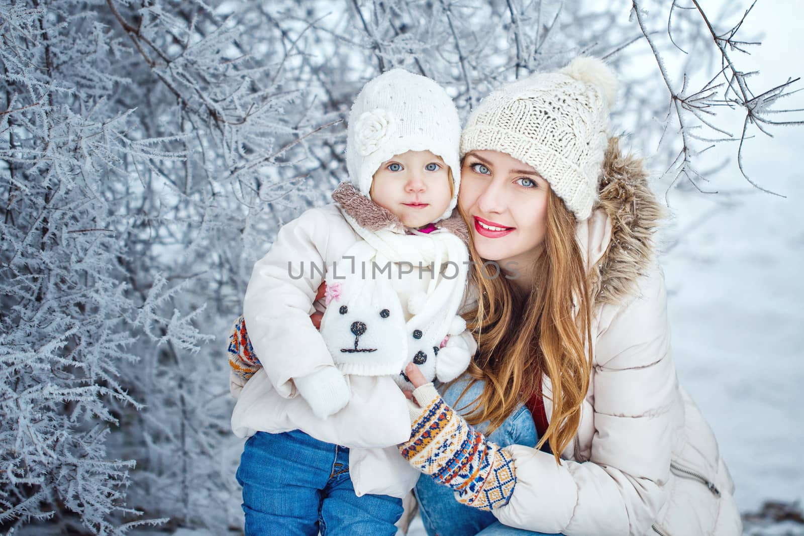 Mother holds daughter on hands in winter forest by Vagengeym