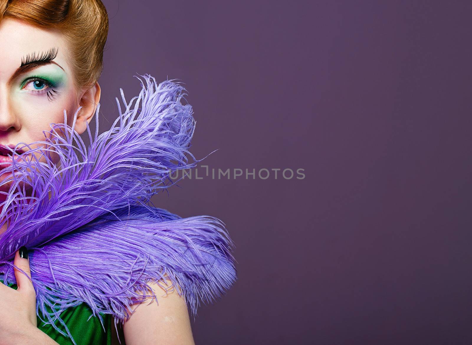 Attractive young girl with a fabulous makeup and feathers close-up portrait