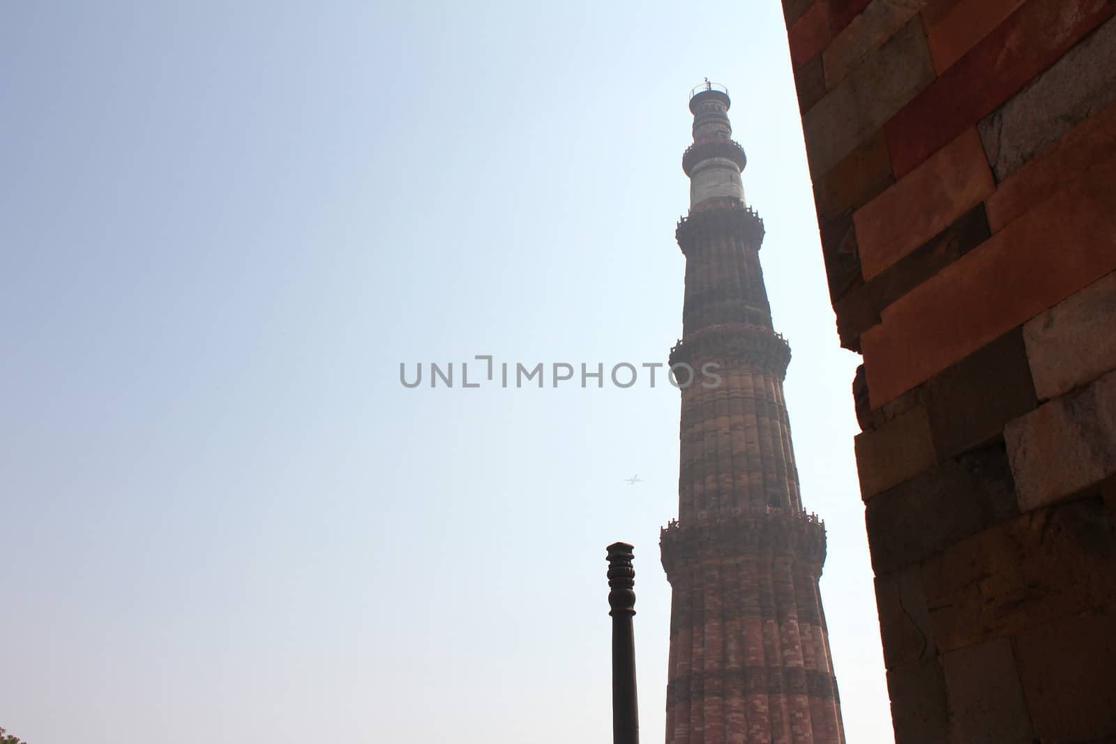 qutub minar with iron pillars in blue sky

