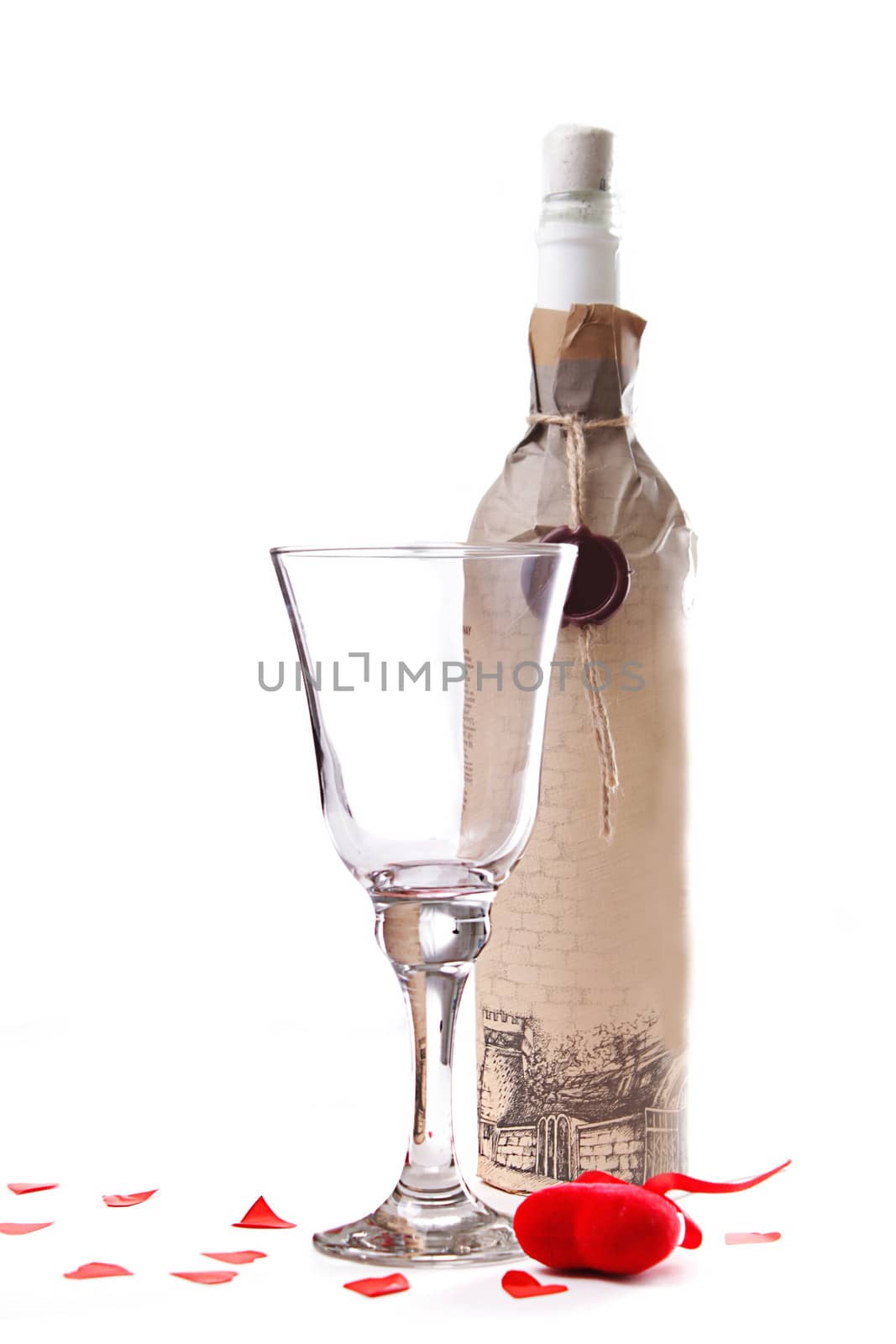 Empty glass of wine and bottle with paper heart isolated over white