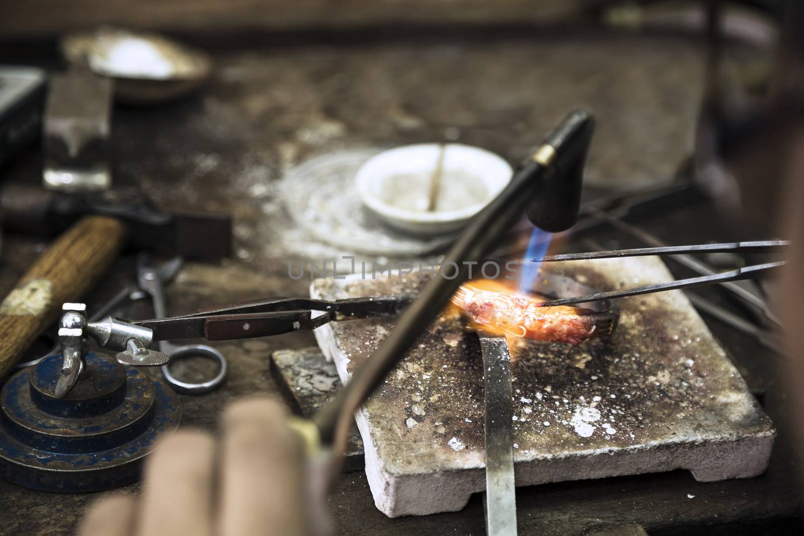 Close up of Jeweler crafting golden rings with flame torch.