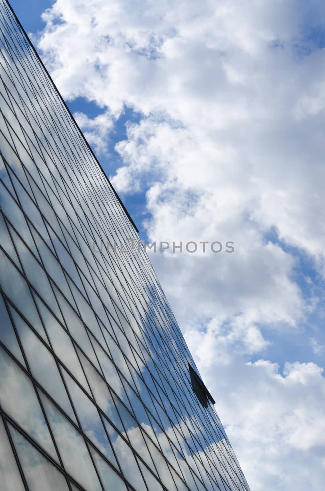 glass surface of a building with reflection of a clouds and sky from above vertically cropped