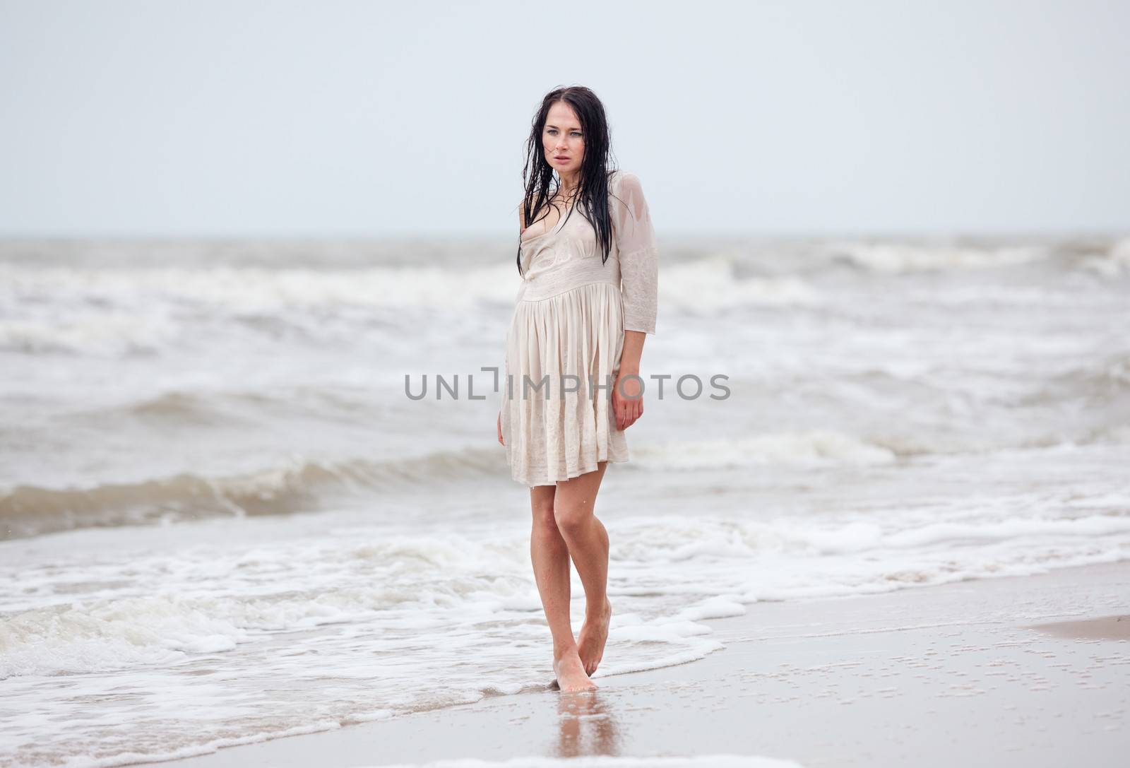 Beautiful young seminude woman in the cold sea waves