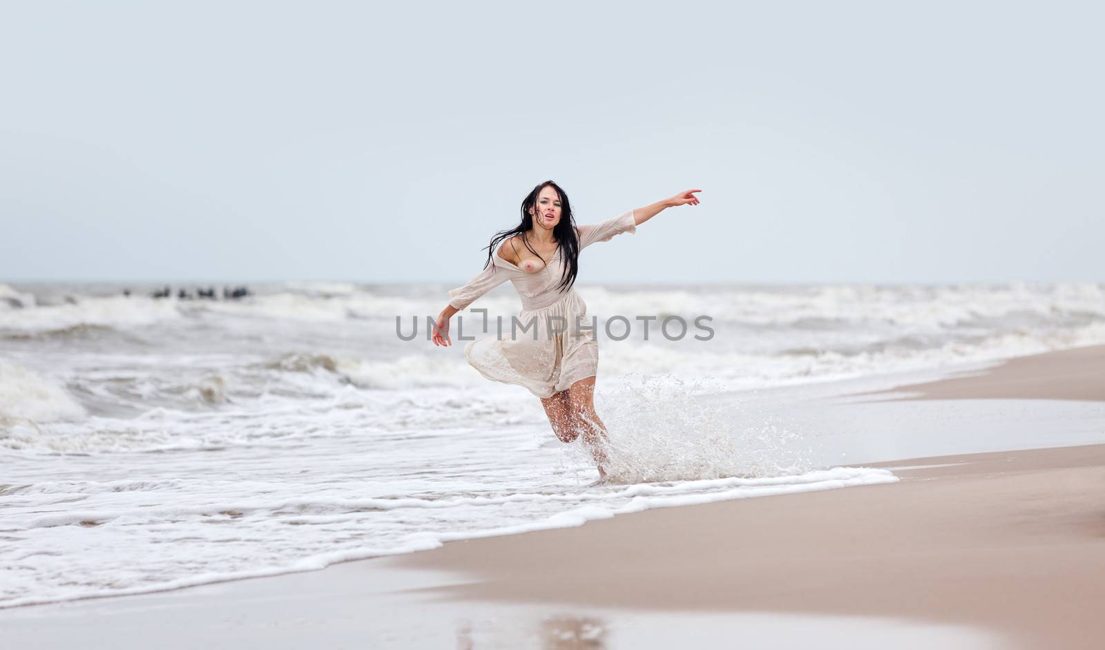 Beautiful young seminude woman in the cold sea waves