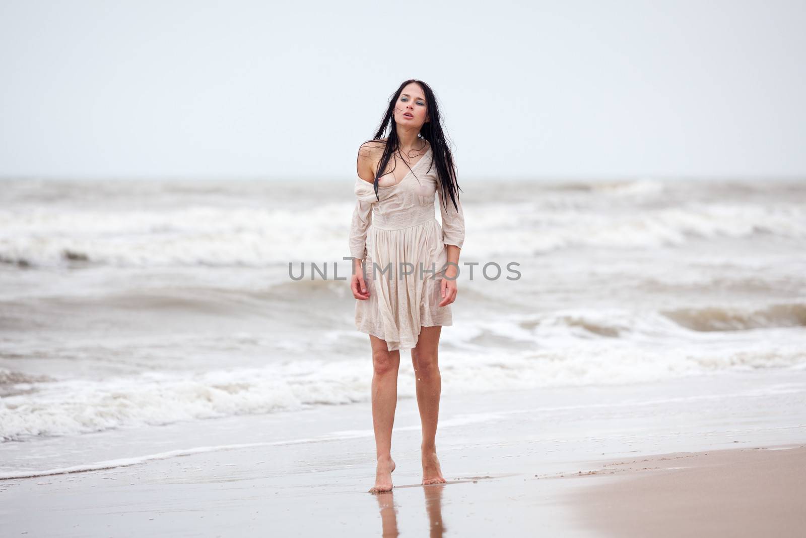 Beautiful young seminude woman in the cold sea waves