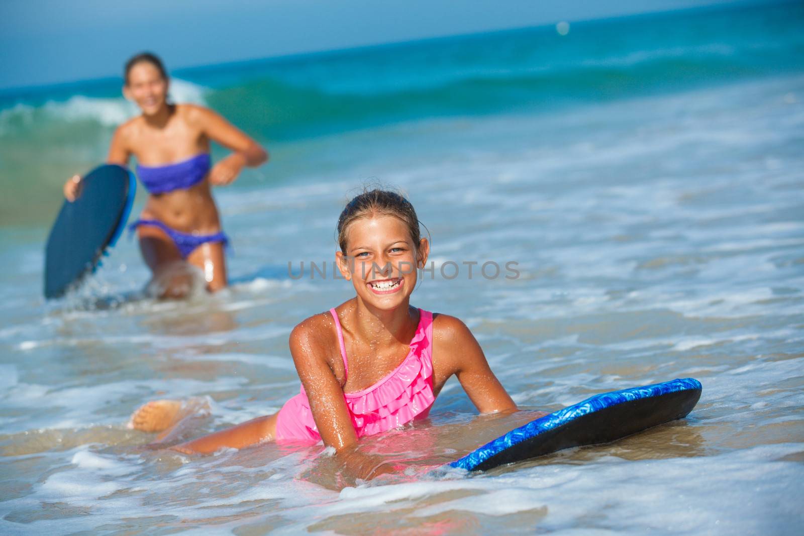 Summer vacation - Two cute girls having fun with surfboard in the ocean