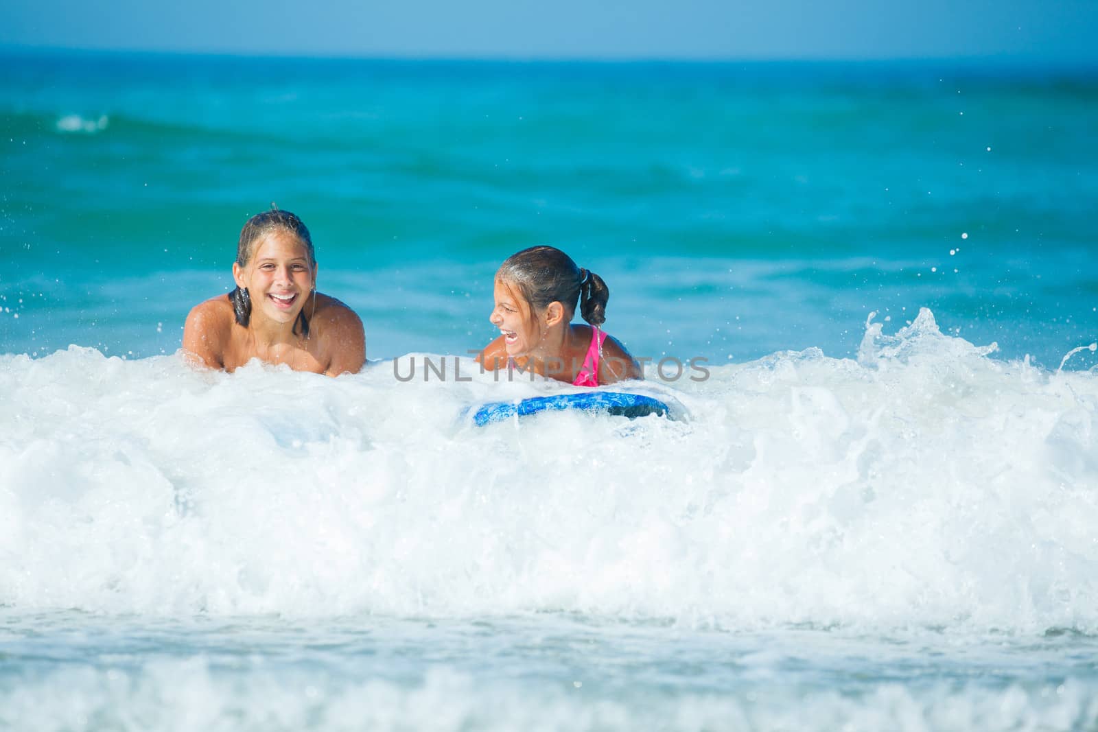 Summer vacation - Two cute girls having fun with surfboard in the ocean