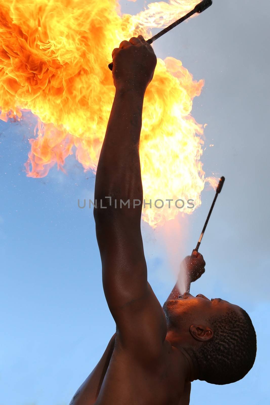 Circus fire-eater blowing a large flame from his mouth