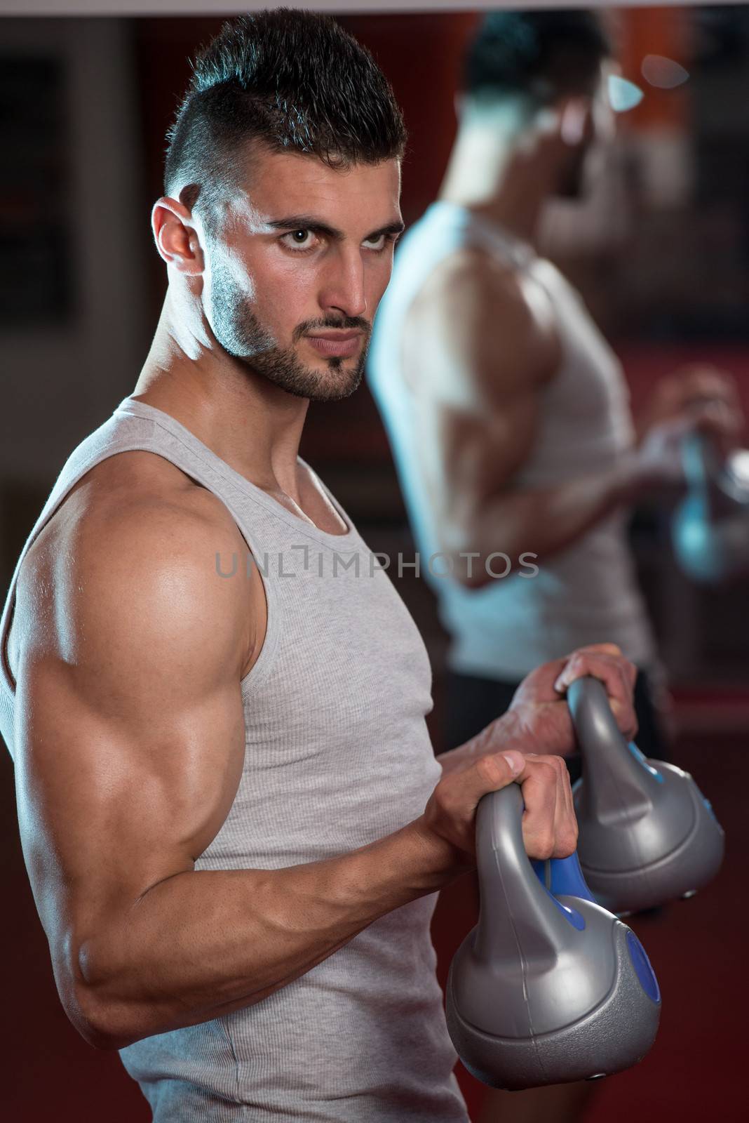 Young Men Lifting Kettle Bell In Gym by JalePhoto