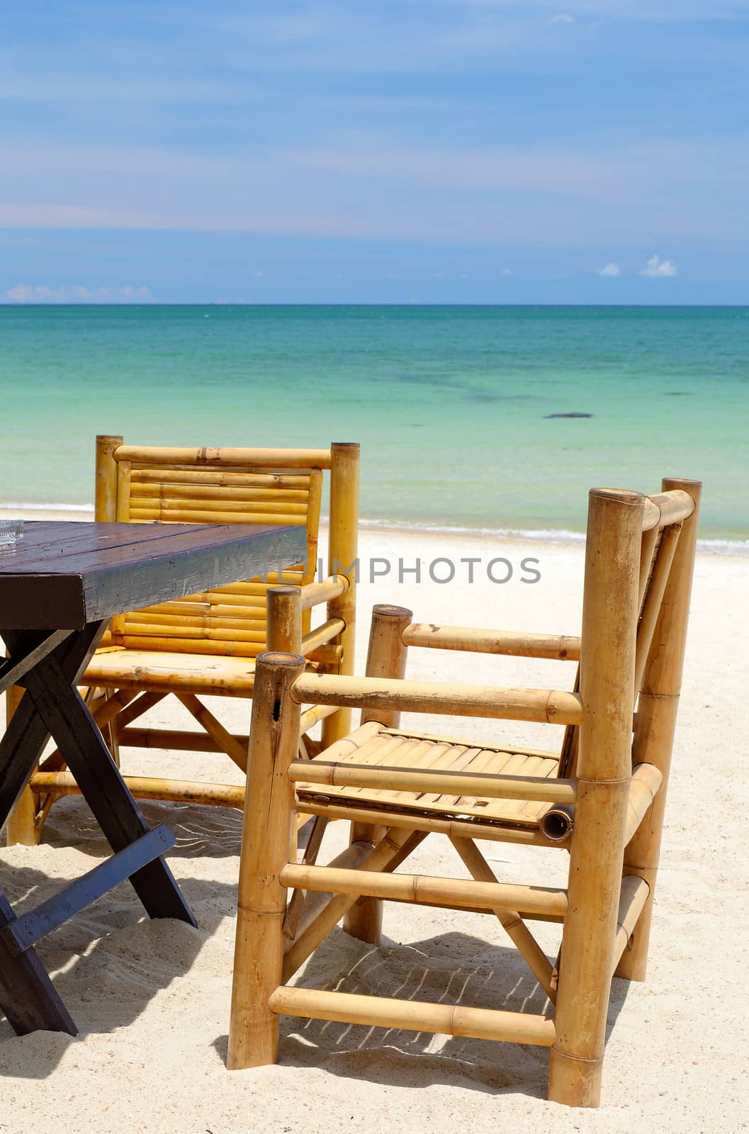 Chairs and table on the coral sandy beach with turquoise transparent water in the background, Koh Phangan, Thailand.
