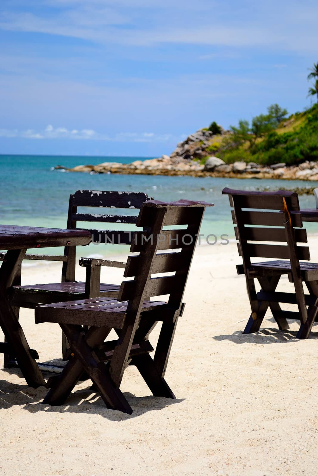 Chairs and table on the coral sandy beach with turquoise transparent water in the background, Koh Phangan, Thailand.