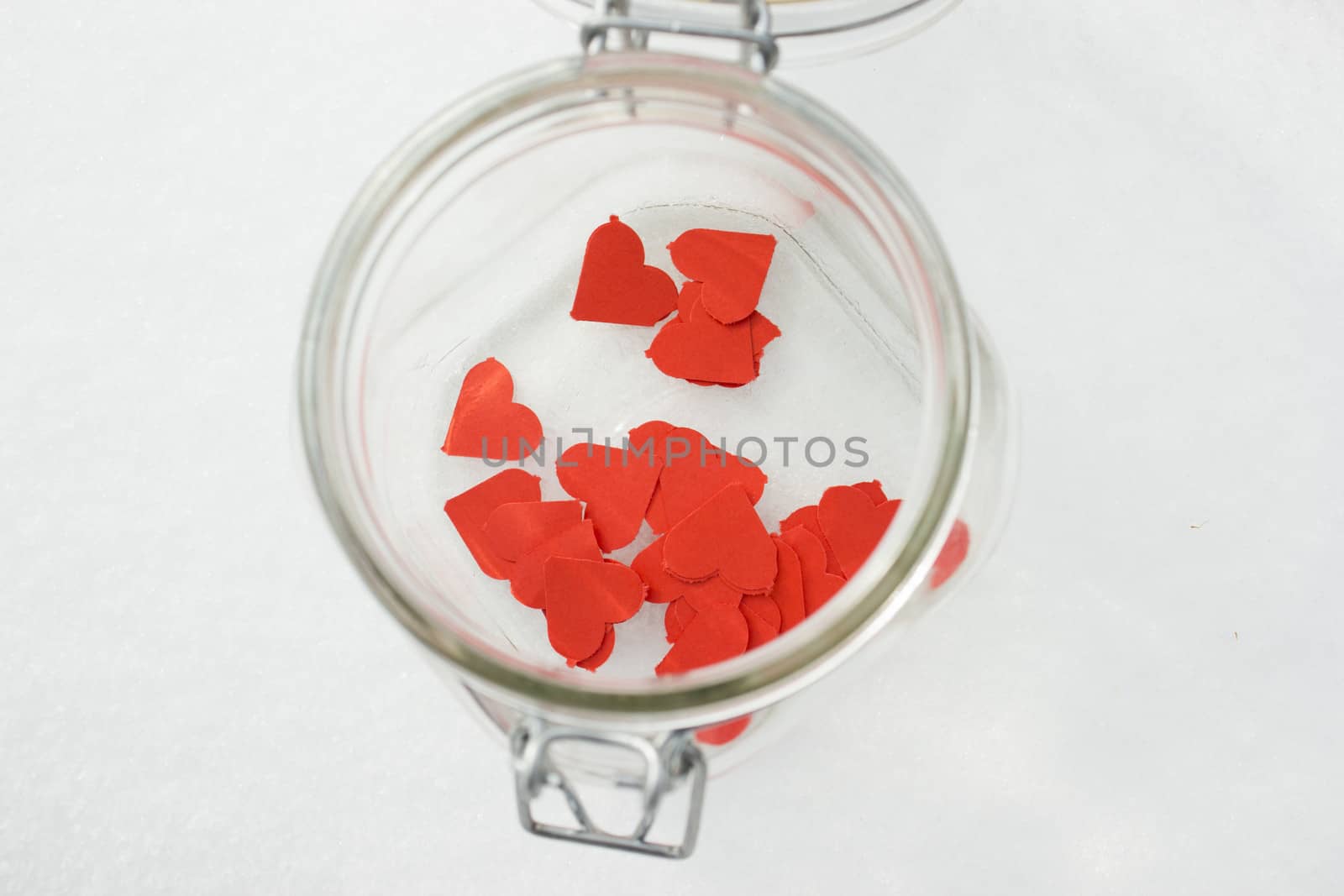 Red  paper hearts in a jar on a snow winter background.