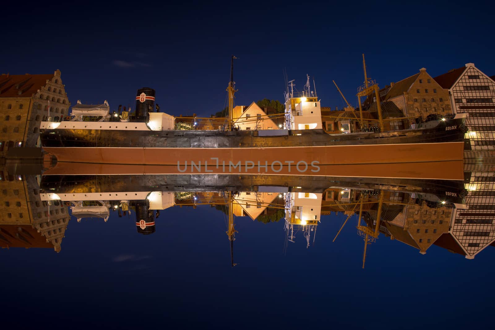 Mirror view of the Soldek at night in the river Motlawa, famous ship in the old port of Gdansk.