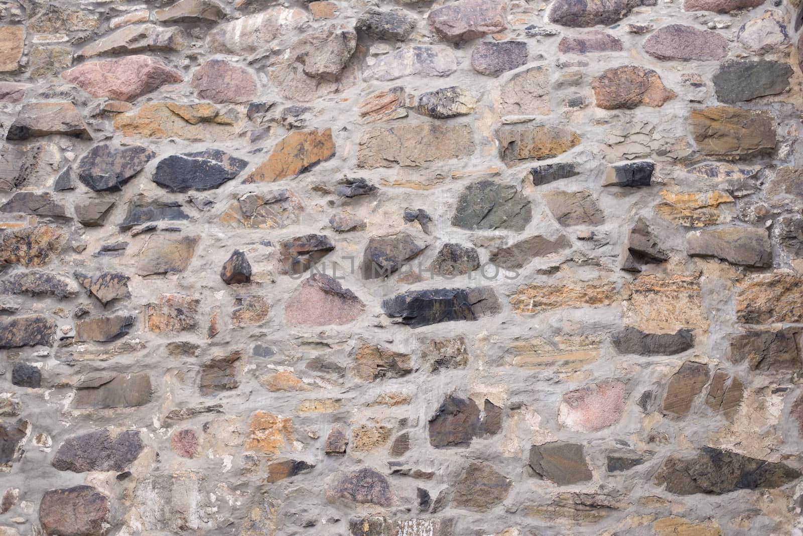 Old field stone wall background with stones of different colors