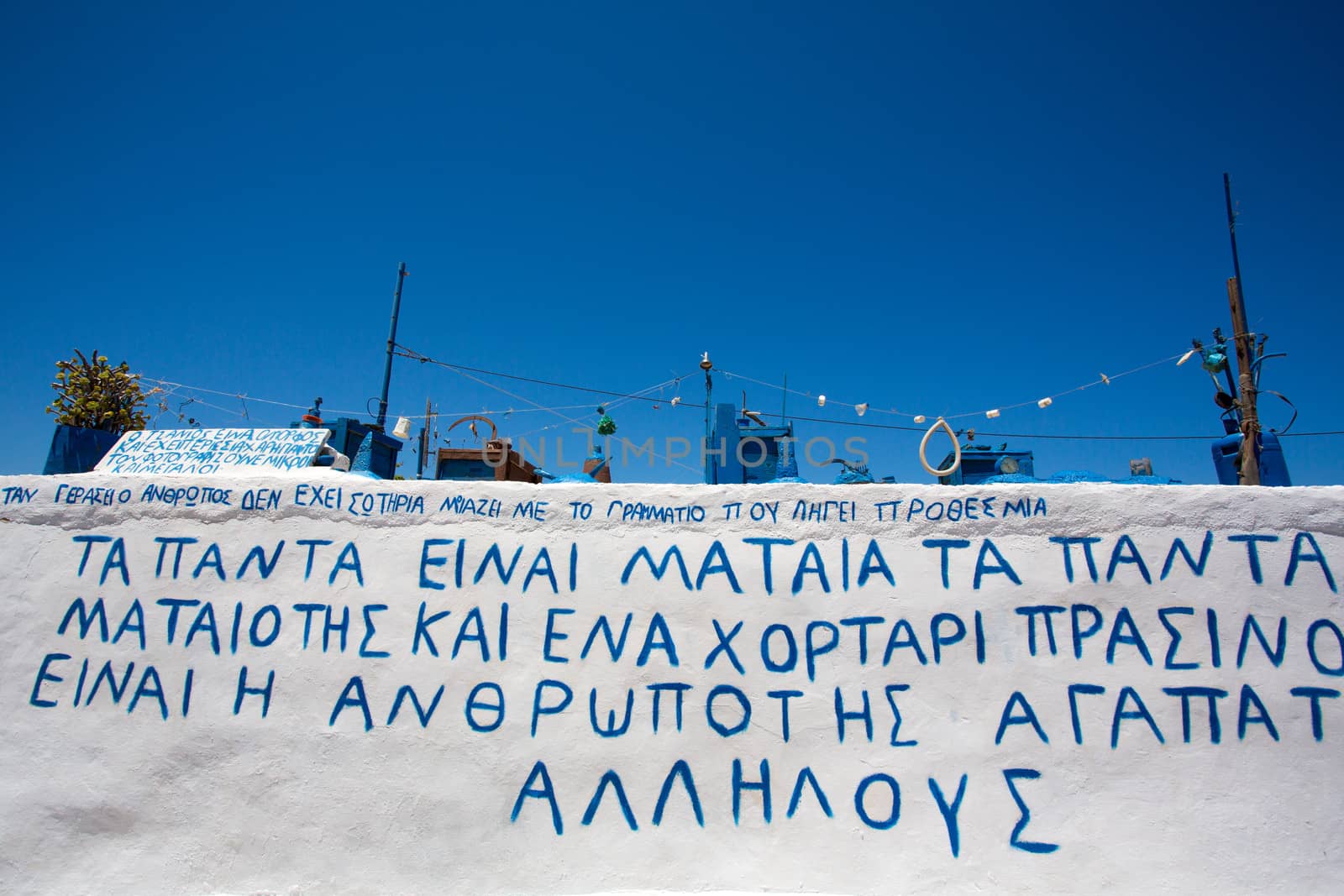 Artistic installation on a  roof of a house in Folegandros, the installation is made of strange objects all painted in blue, There is also a message about the crisis in Greece.