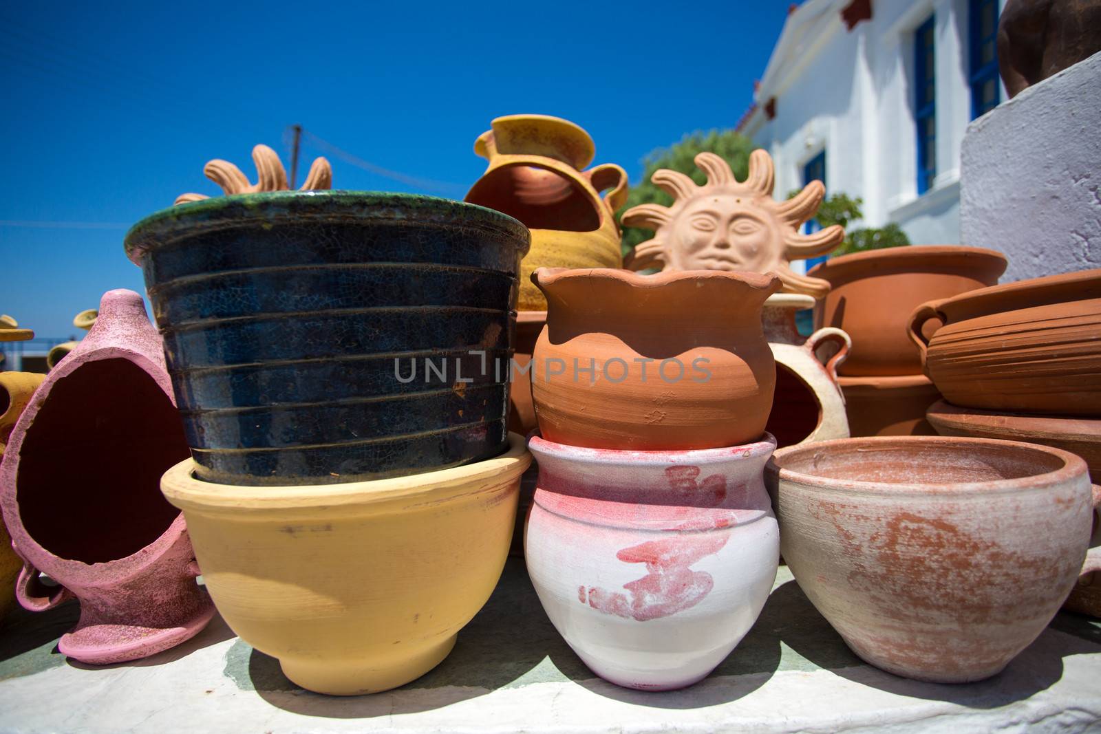 Various ceramic pots and other objects for sale at a local market, in the background the typical white and blue houses of Folegandros, greece, 2013.