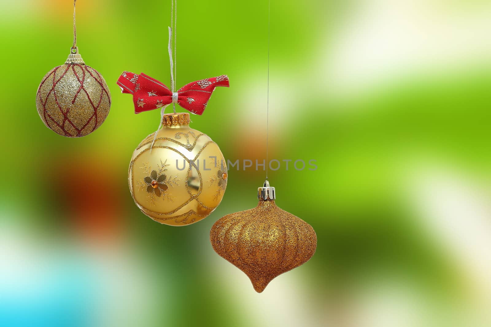 three gold christmas baubles on green out of focus background