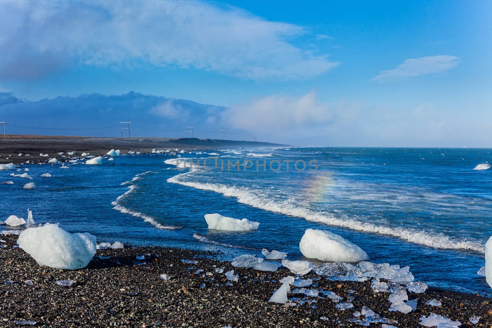 Beautiful beach in the South of Iceland with a black lava sand is full of icebergs from glaciers not far away.