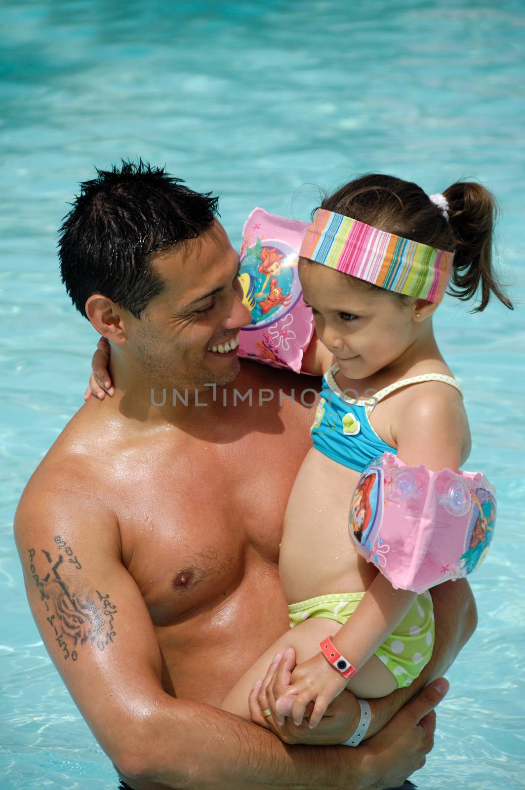 Happy man and child in pool. The mand is smiling and holding his child.