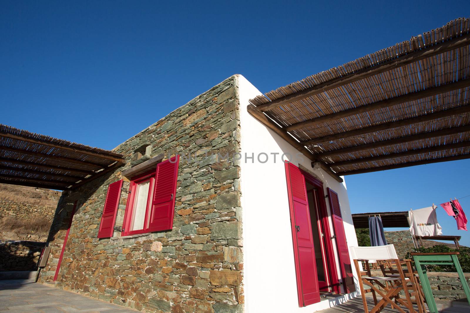 Typical Greek terrace at Folegandros, and a view of a hotel room and flashy red doors. In most of the Cycladic islands, houses were painted white to reflect the harsh summer sun.