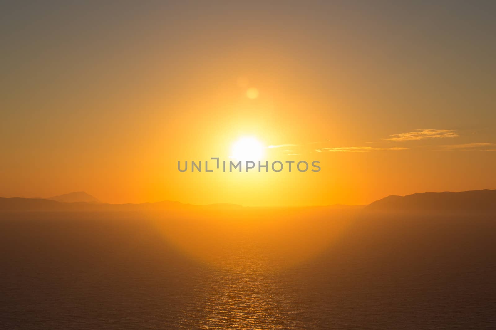 Beautiful view of the shoreline at sunset, the aegean sea, the rocky mountains and in the distance a typical white habitat of Folegandros, an amazing island from Greece 2013.