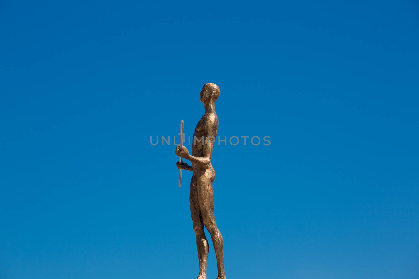 Statue made of bronze of a naked man in the blue sky of santorini, Greece 2013.