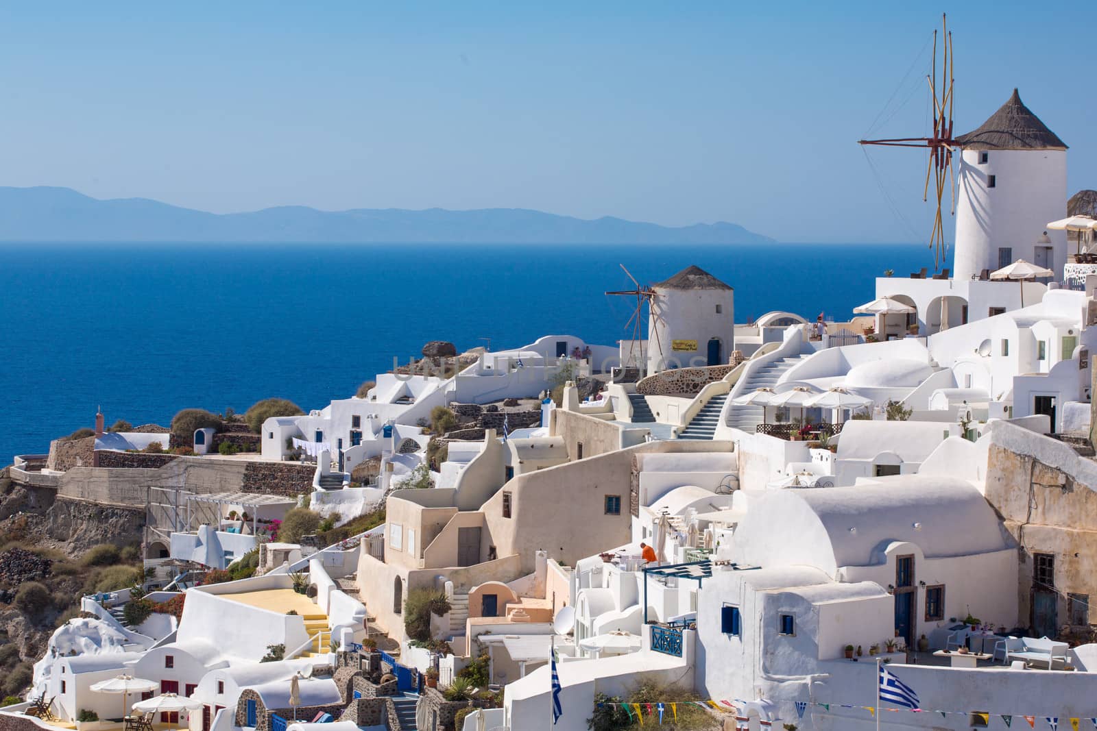 The Windmill in Oia, the latest and the best village for sunset on the island of Santorini, Greece. All the houses are white but dring the sunset, it all become orange.