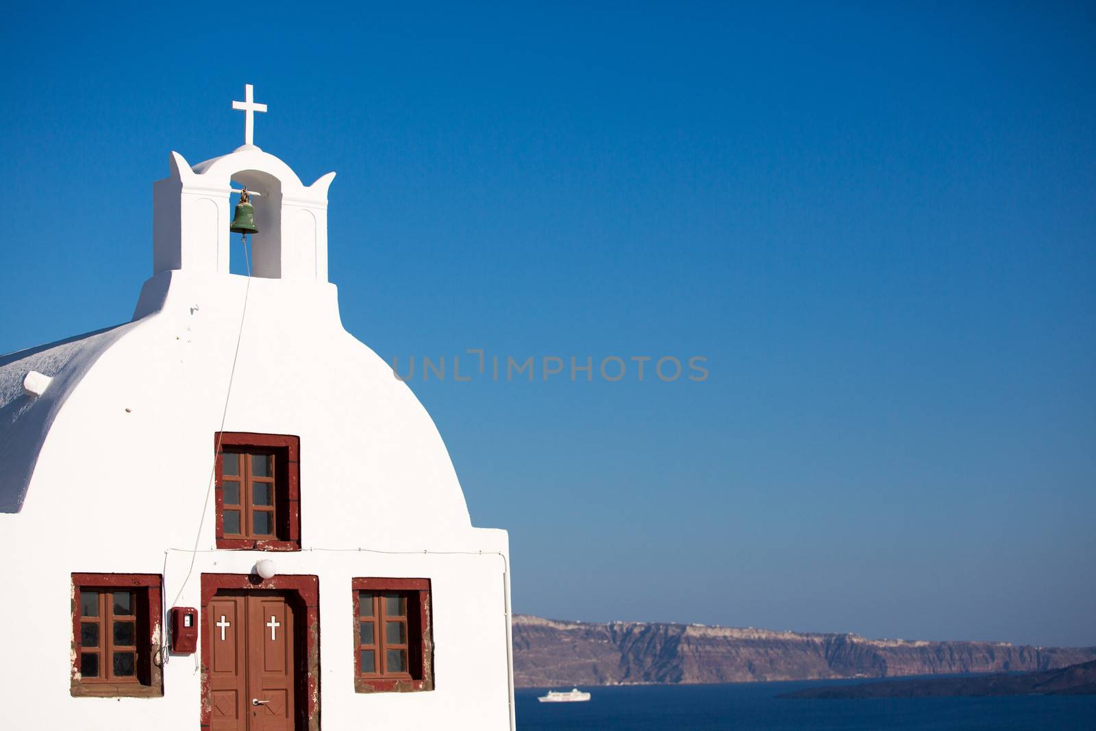 A small church overlooking the caldera in Oia, Santorini.In the distance you see one of the many cruise-boats crossing the aegan sea. greece, 2013