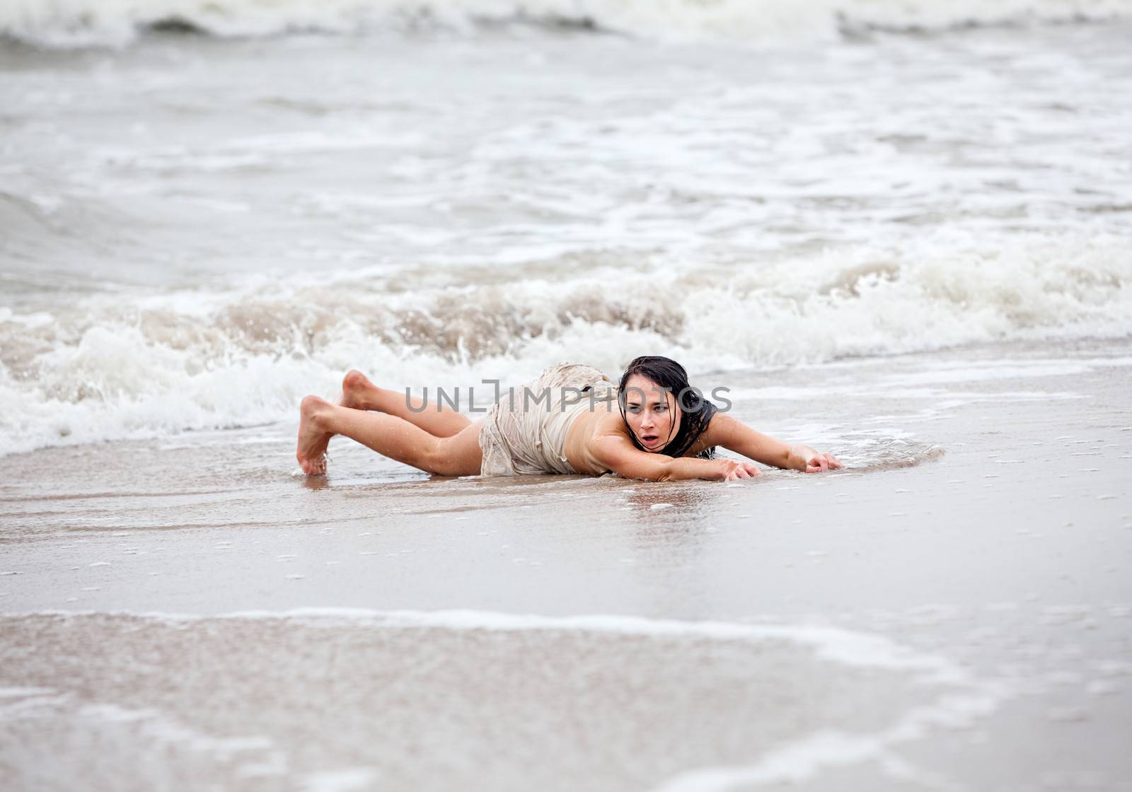 Beautiful young seminude woman in the cold sea waves