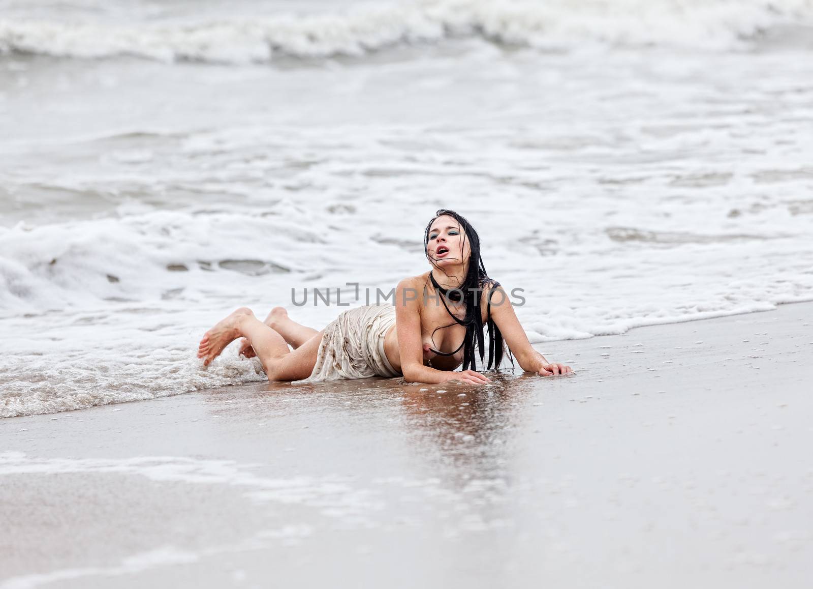 Beautiful young seminude woman in the cold sea waves