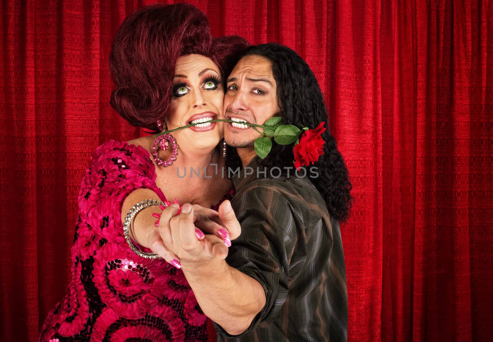 Embarrassed man with rose in mouth dancing with drag queen 
