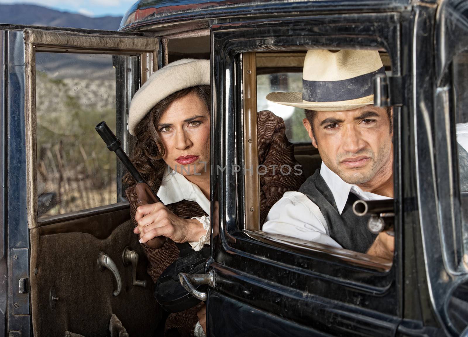 Serious retro gangsters in car with machine guns