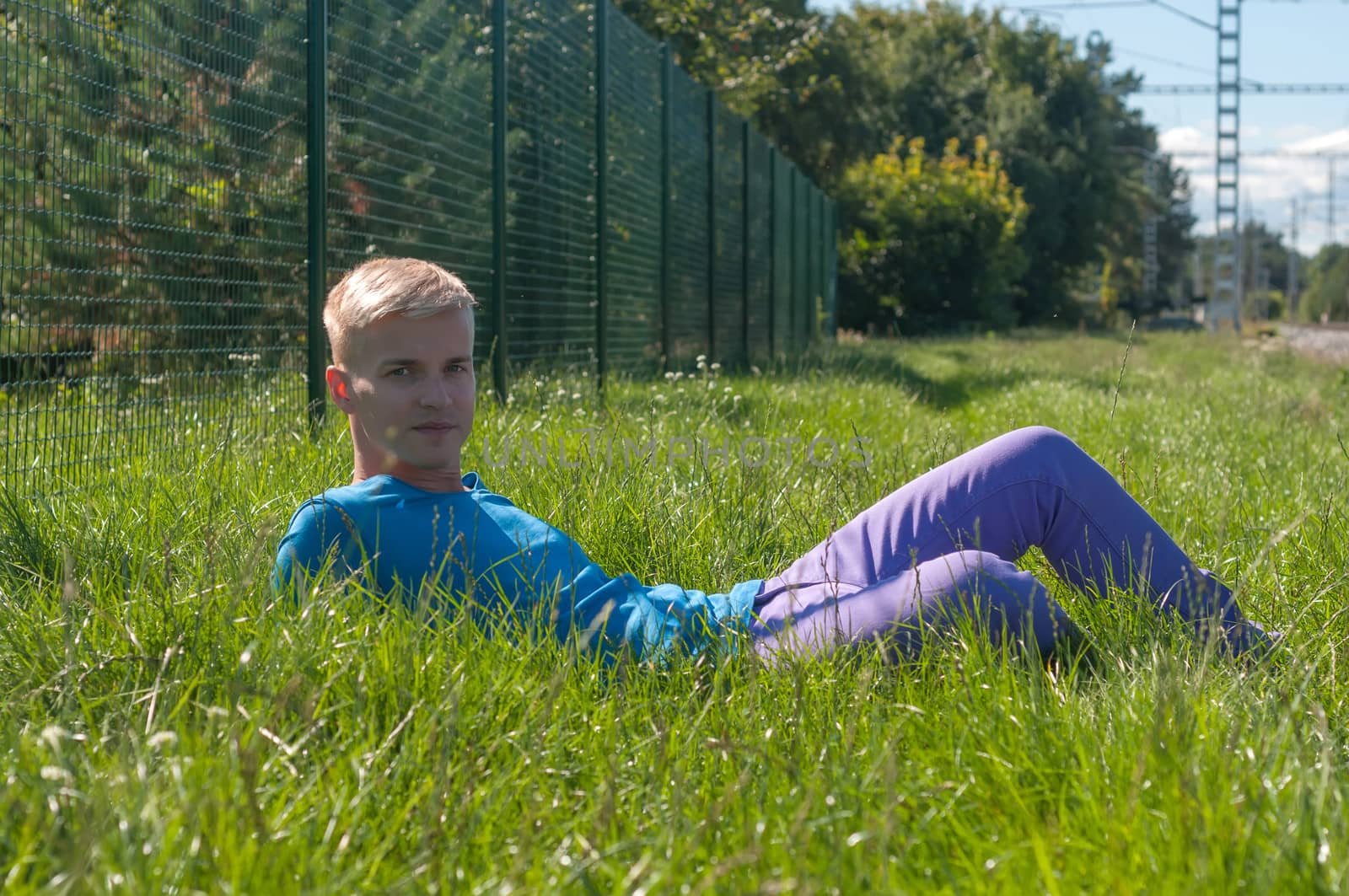 Young an in blue t-shirt lying in a grass