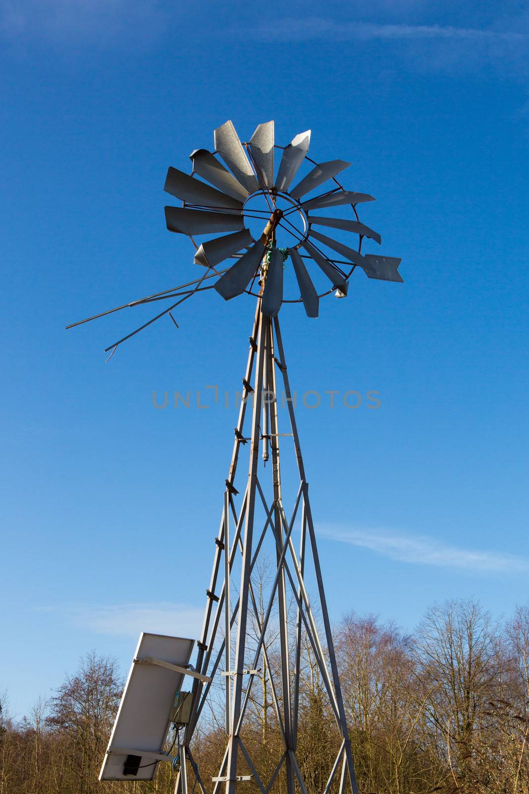 Windmill on a farm in France with blue sky in the background and wild nature around