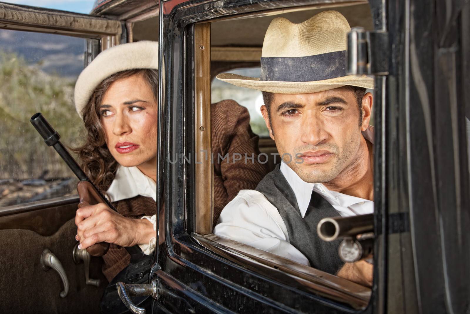 Gangster couple on lookout in their antique automobile