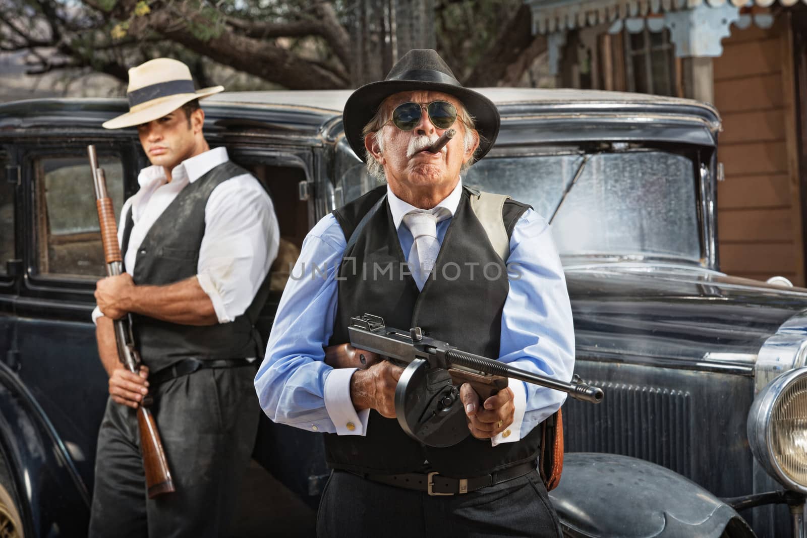 Serious mob boss with gun and guard near car
