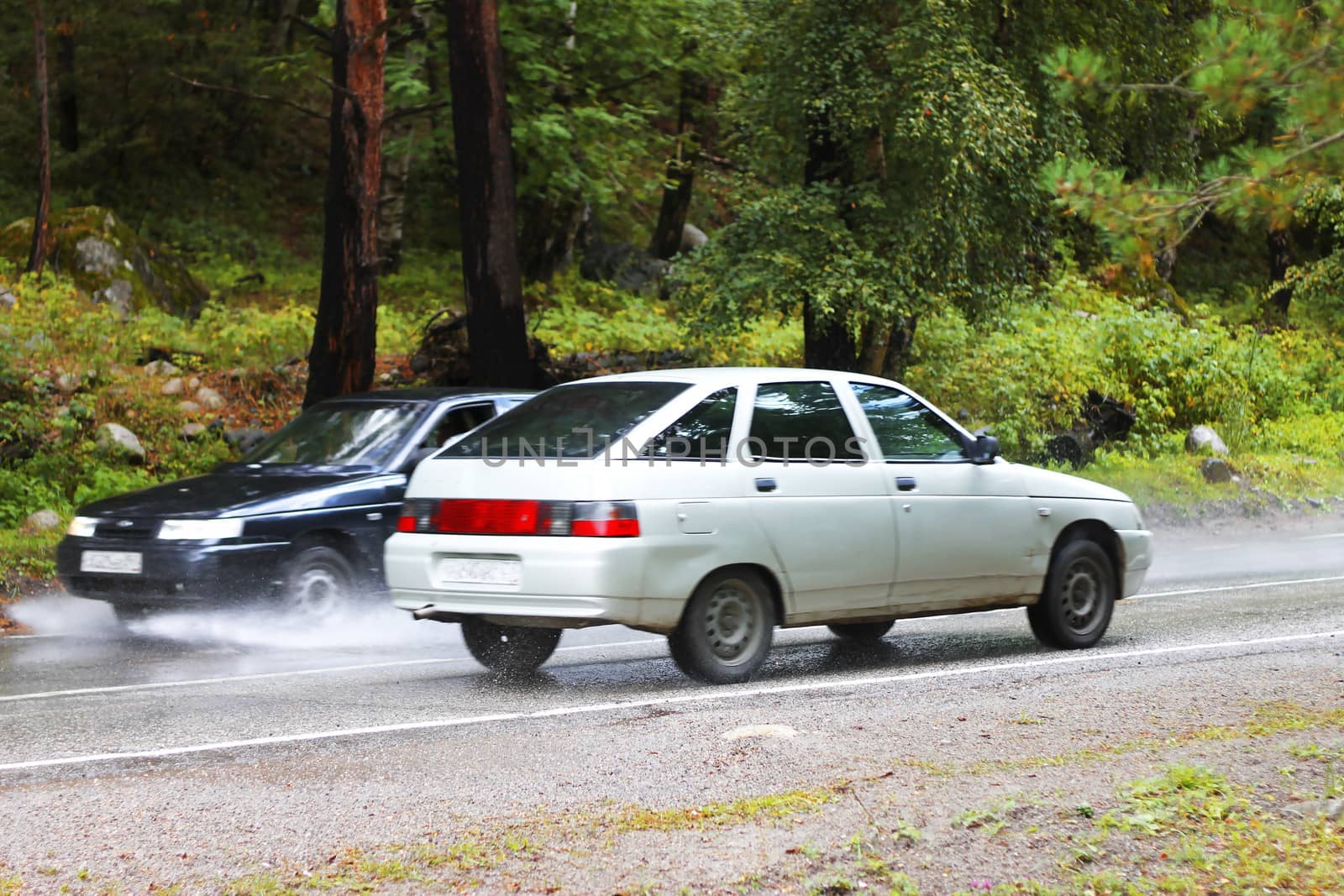 Automobile driving on the puddle on a highway