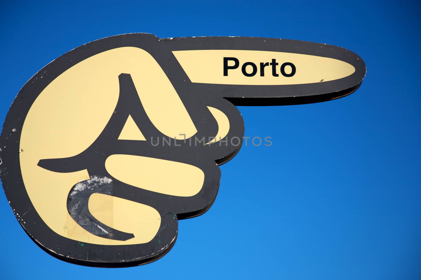 Board with hand pointing the direction to the port of Porto with a fresh blue sky