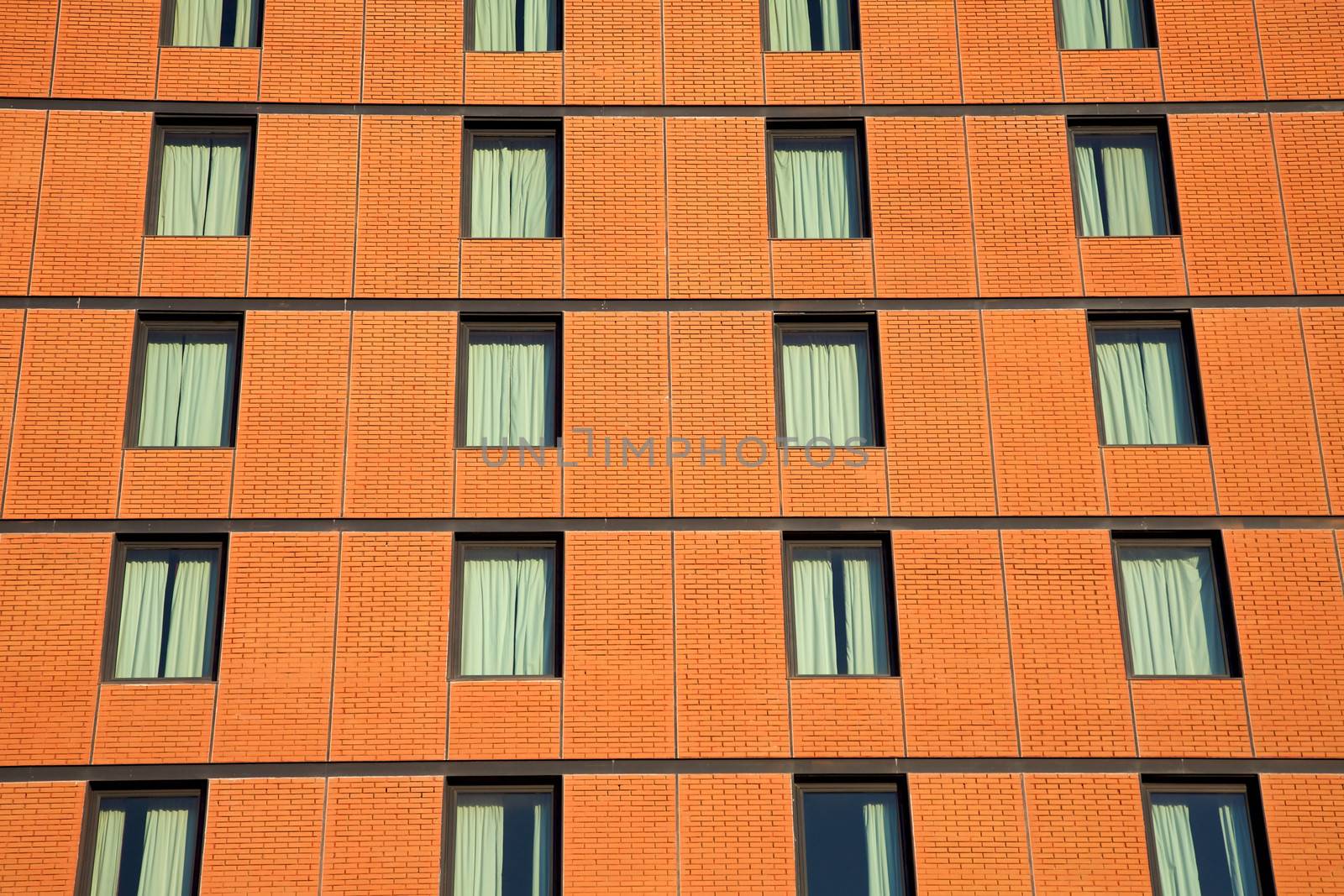 Facade of a brick office building with successive rows and floors of tinted glass windows.