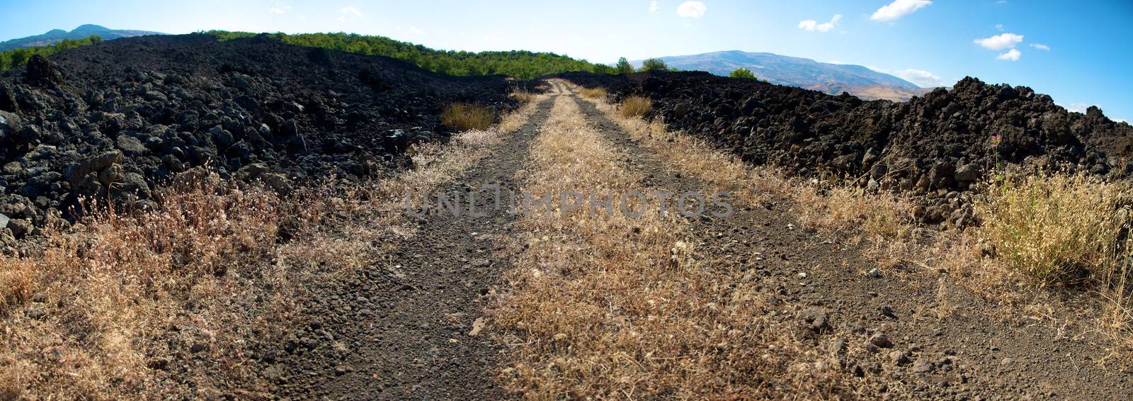 Track cross old volcanic fields with mountains in the background