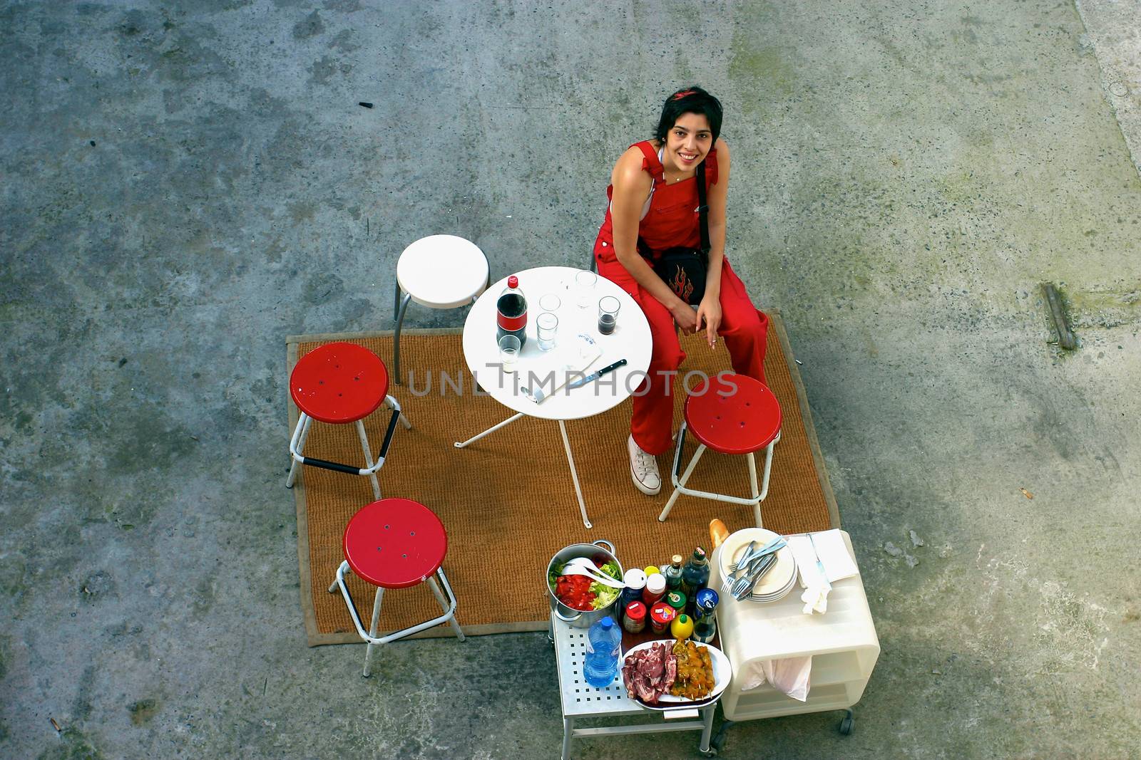 BRUSSELS, BELGIUM, JUNE 17: View from top of an indentified woman smiling and dressed in red, sitting at a pic-nic table ready for 4 people during a sunny afternoon. Brussels in 2004.