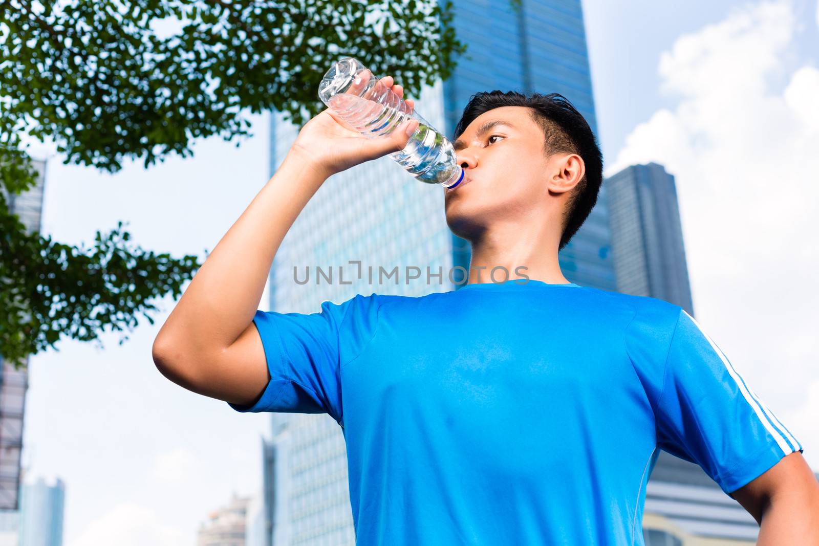 Urban sports - Asian Indonesian man doing fitness in the city on a beautiful summer day