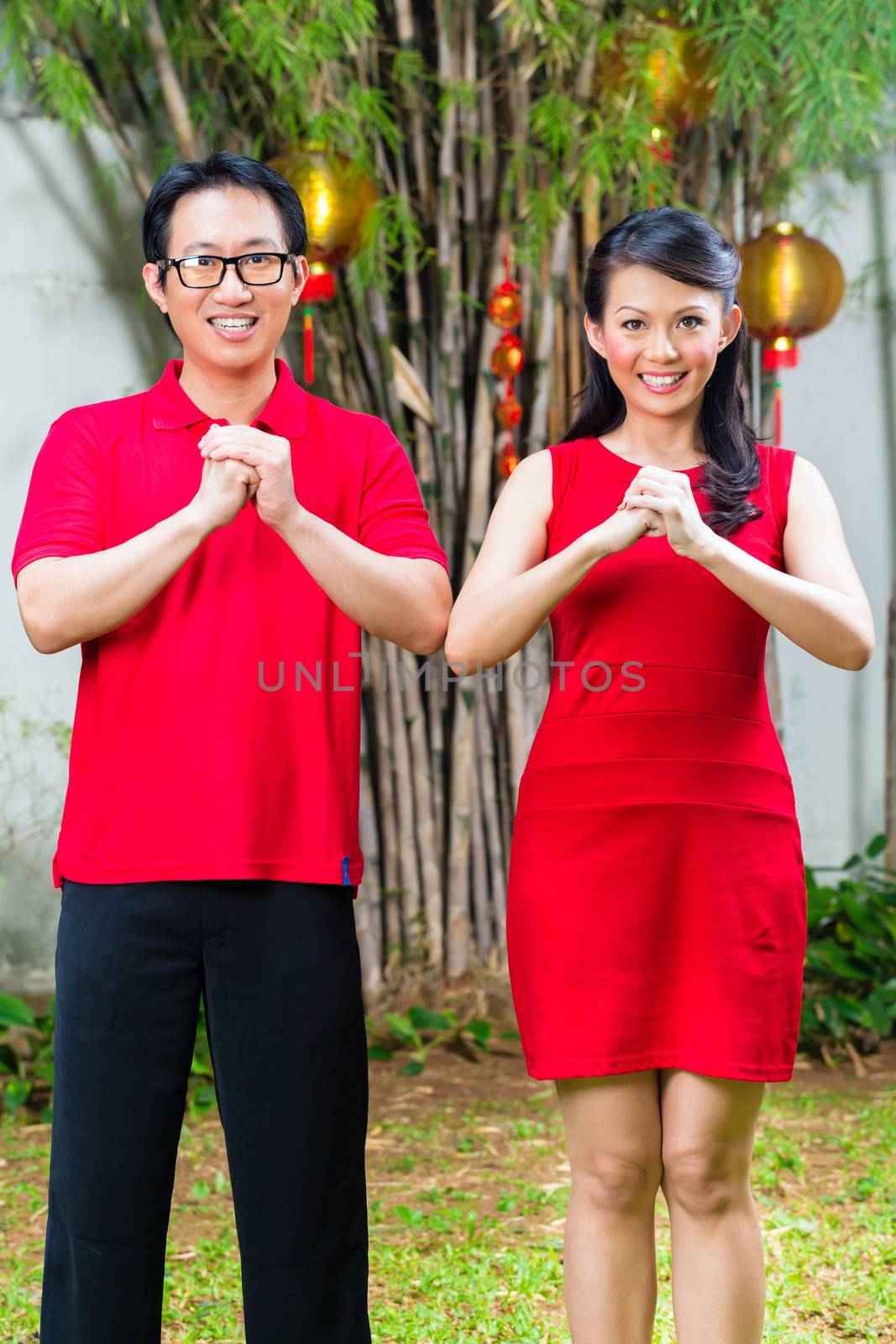 Couple celebrating Chinese new year traditional greeting, wearing red
