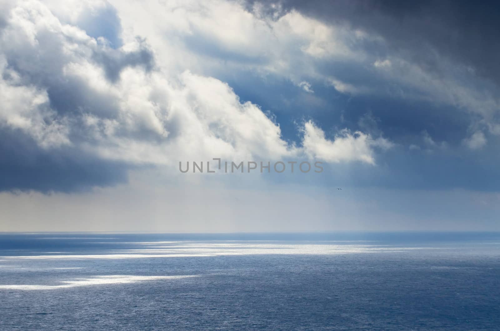 Cloudy blue sky above a blue surface of the sea