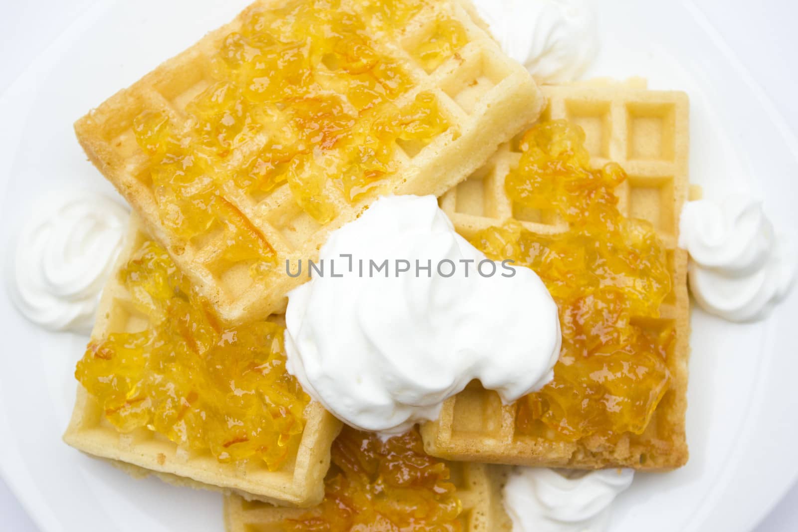 Toasted waffles with orange jam and cream on top.