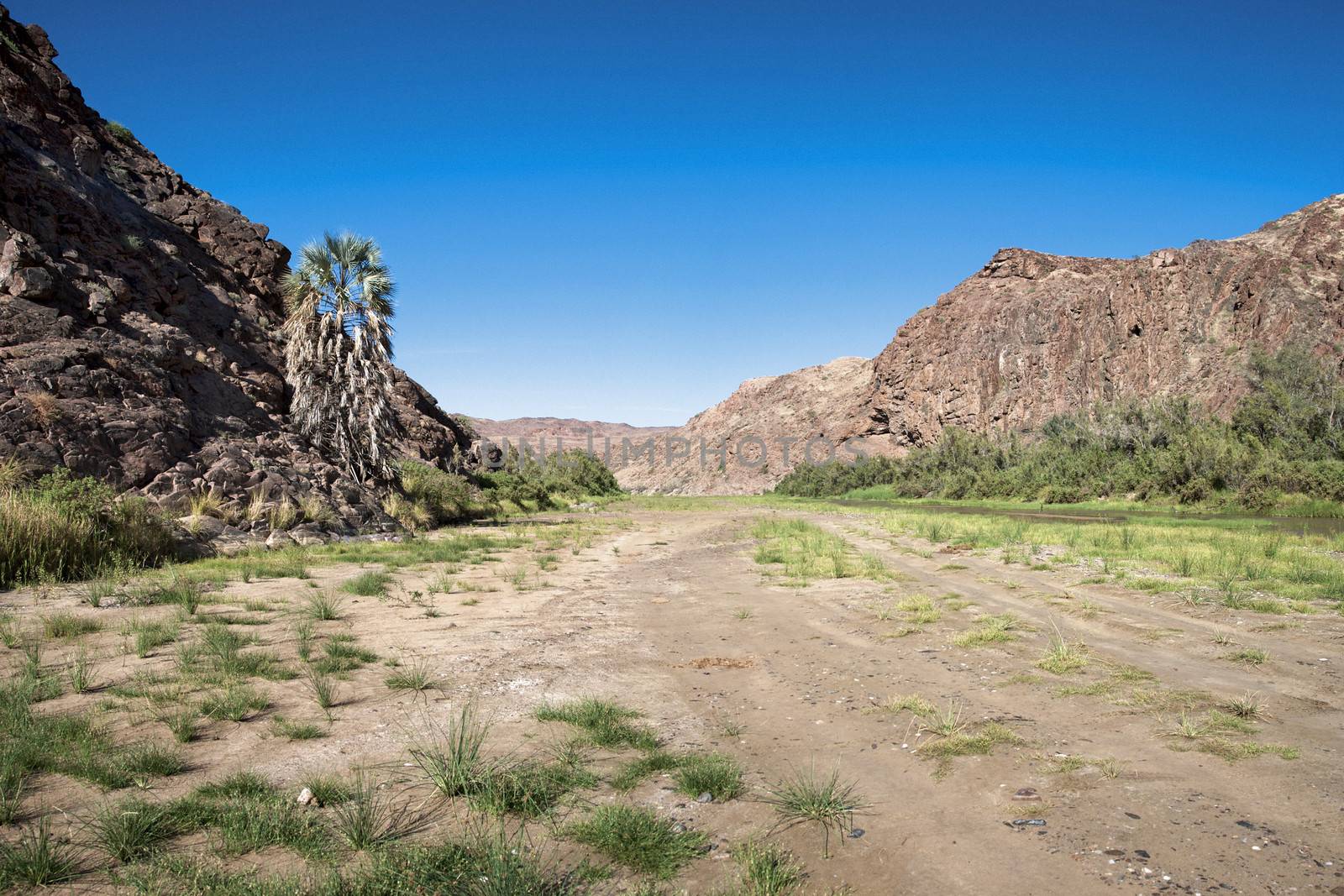 Kaokoland game reserve in Namibia, sand track going toward the Skeleton Coast Desert with a blue sky